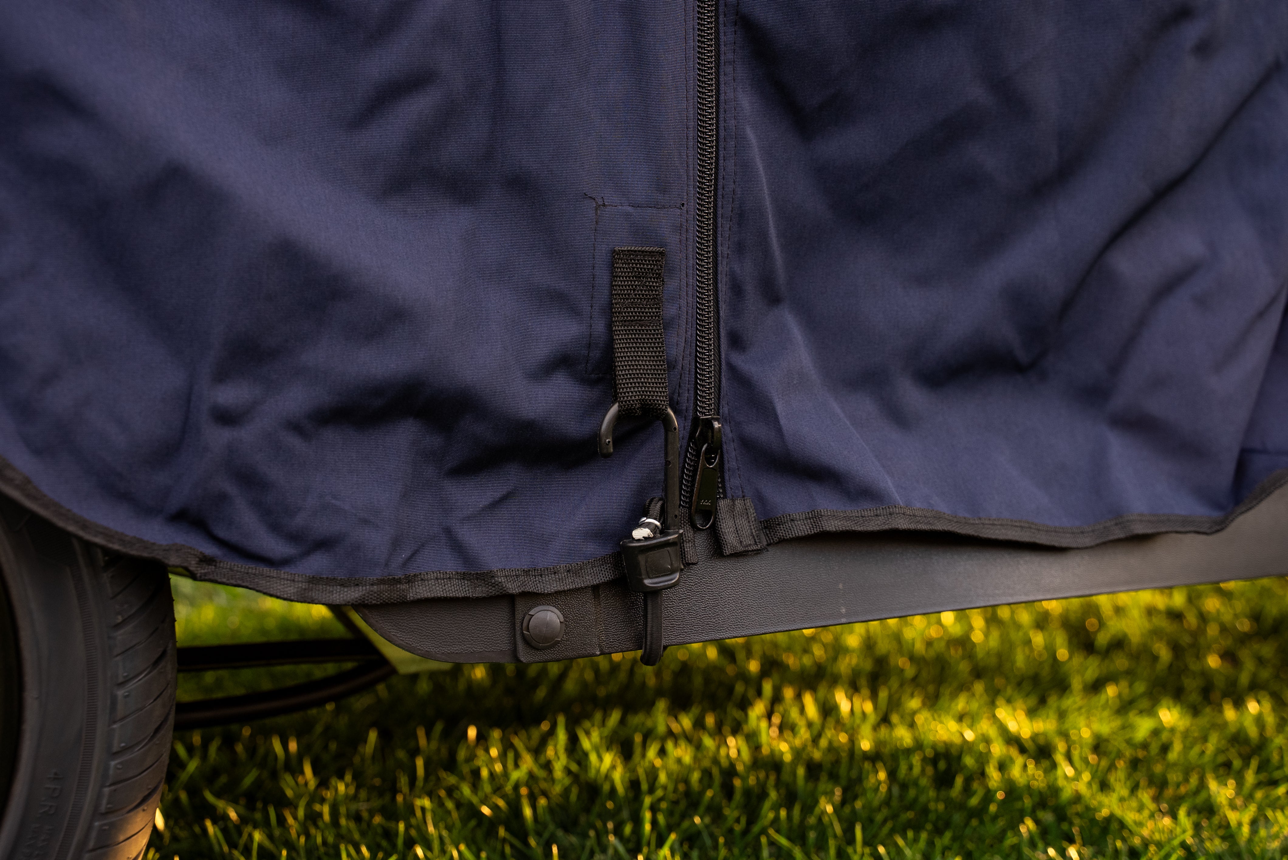 Close-up of heavy-duty bungee hook securing Navy Clear Vision cover to cart frame