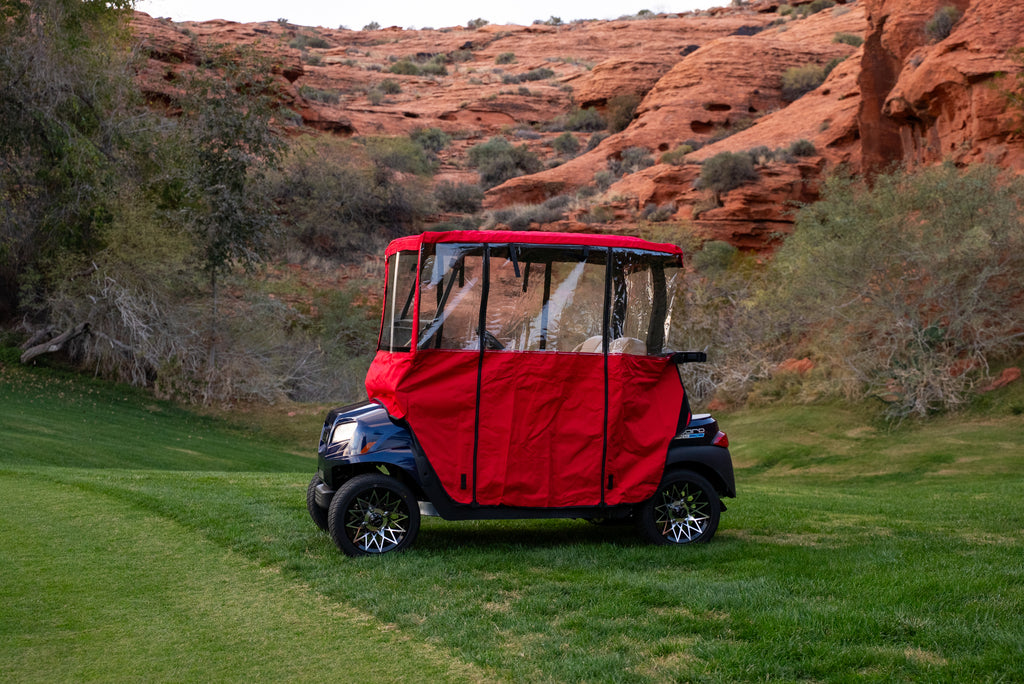 Red Clear Vision Golf Cart Cover with clear wraparound windows on green fairway