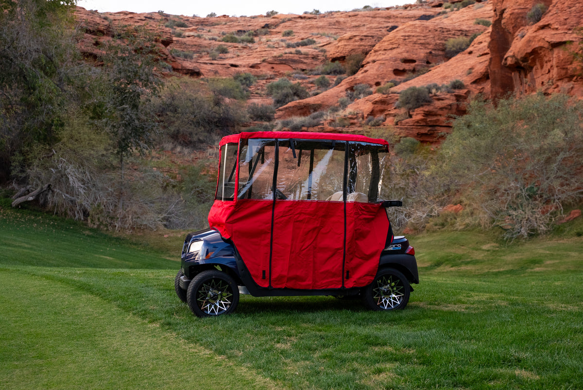 Red Clear Vision Golf Cart Cover with clear wraparound windows on green fairway
