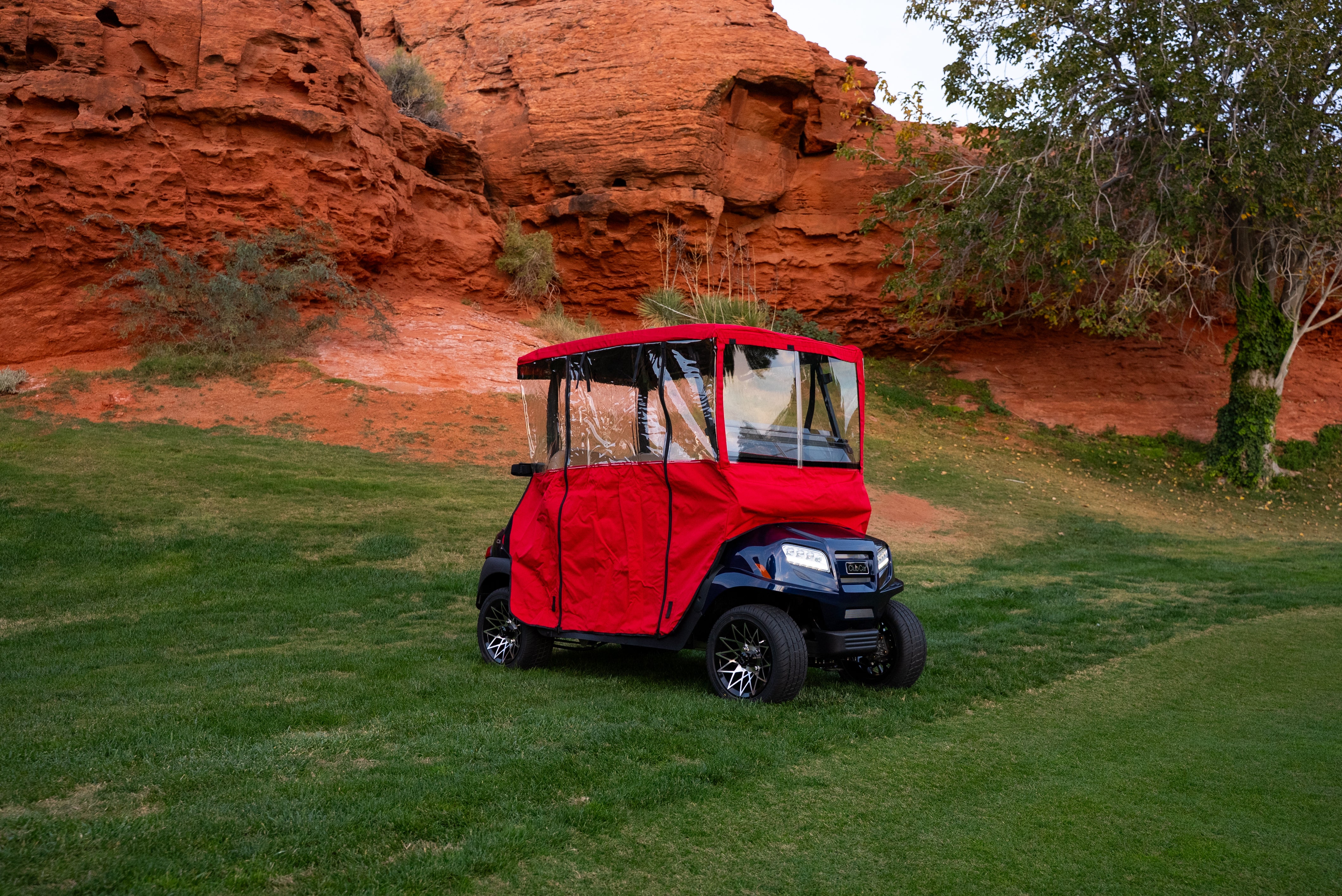 Red Clear Vision cover on navy golf cart, headlights on, desert course backdrop