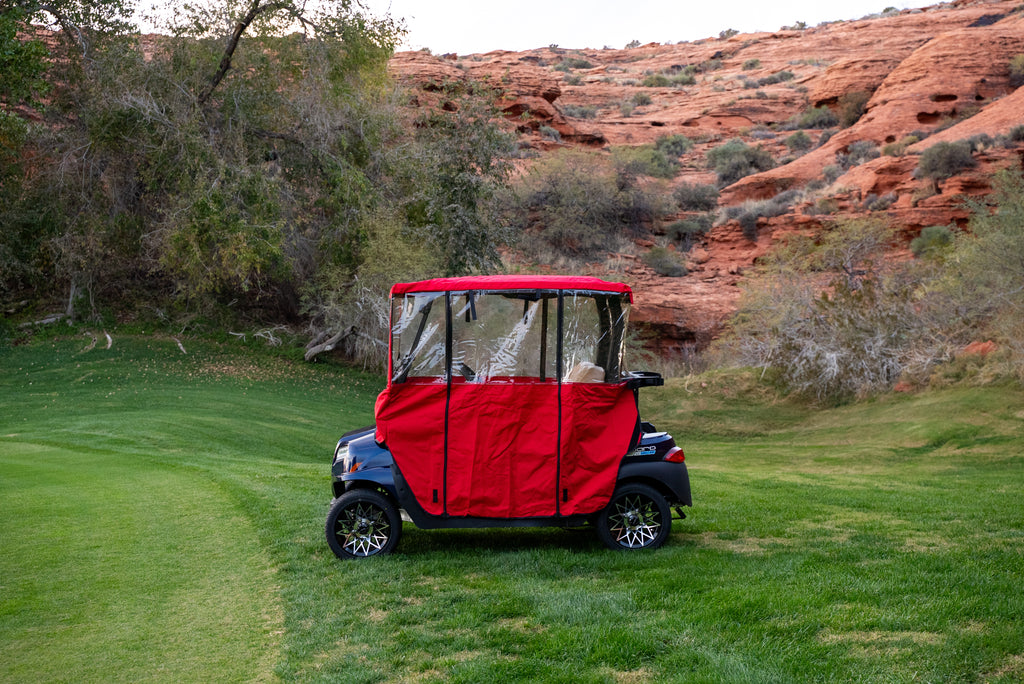 Red Clear Vision Golf Cart Cover installed on a dark cart against red-rock cliffs